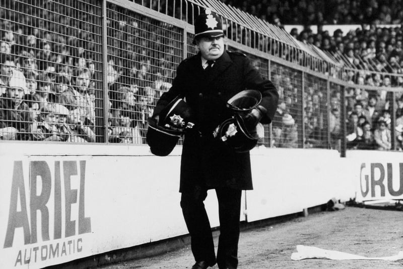 Isolated trouble broke out on the terraces at Elland Road in February 1987. Pictured is a policeman collecting helmets which were knocked off.
