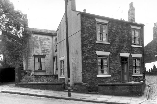 Two properties on Armley Ridge Road. On the left, in the background, is number 11, the doorway of this property is hidden behind the gable end of number 13 which follows to the right. The entrance to Barleycorn Yard can just be seen on the right edge.
