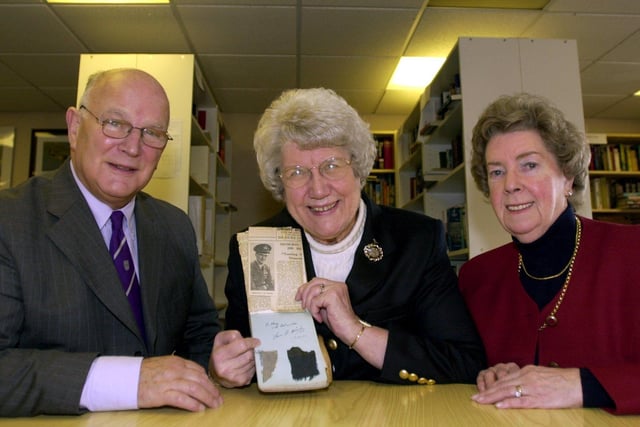 Mary Way hands over an autograph book featuring the signature of Flight Lieut Nicolson and burnt rags from his jacket to The Second World War Experience Centre in Horsforth in December 2003., She is pictured with Dr Peter Liddle, Second World War Experience Centre director and volunteer Brenda Clifton.