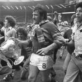 Mick Harrison, accompanied by jubilant Leeds fans, takes the Challenge Cup on a lap of honour at Wembley in 1978. Picture by Steve Riding.