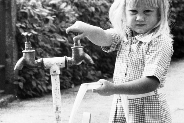 Young Julie Greensmith gets water from a standpipe.