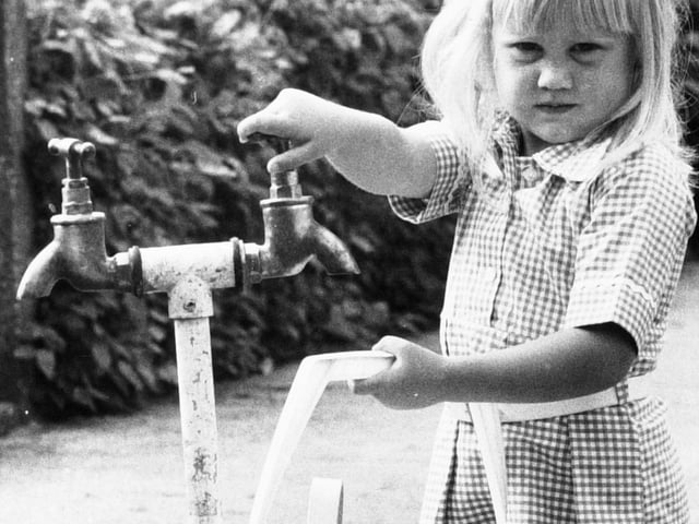 Young Julie Greensmith gets water from a standpipe.
