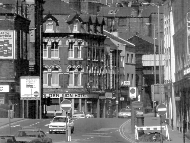 View looks from Hunslet Road towards Bridge End and Lower Briggate. The tall building on the left is the rear of the former Leeds City Transport offices now the Malmaison Hotel. Also on the left there is a glimpse of Leeds Bridge and behind it the business of Alpha Music at numbers 10 to 18 Bridge End. In the centre is the Golden Lion Hotel at number 2 Lower Briggate which stands at the corner with Sovereign Street.