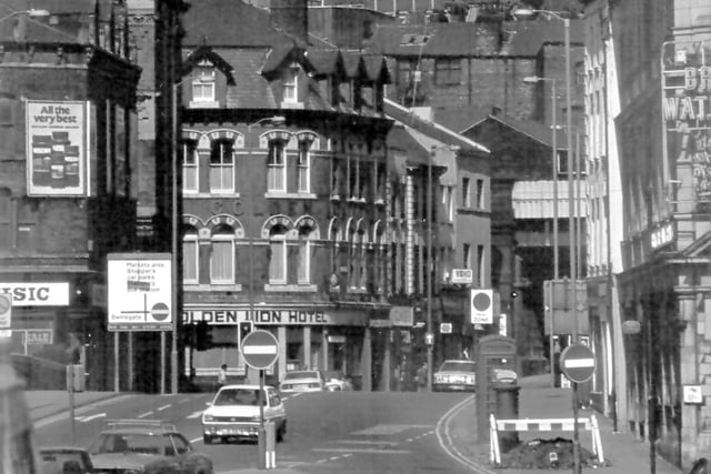 View looks from Hunslet Road towards Bridge End and Lower Briggate. The tall building on the left is the rear of the former Leeds City Transport offices now the Malmaison Hotel. Also on the left there is a glimpse of Leeds Bridge and behind it the business of Alpha Music at numbers 10 to 18 Bridge End. In the centre is the Golden Lion Hotel at number 2 Lower Briggate which stands at the corner with Sovereign Street.