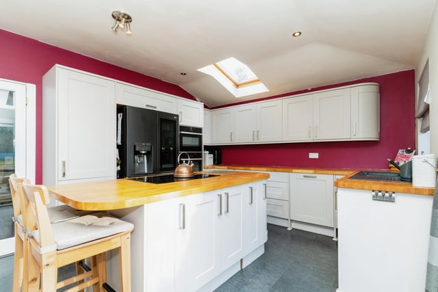 The property benefits from a modern kitchen diner with gorgeous wooden surfaces and contrasting red decor.