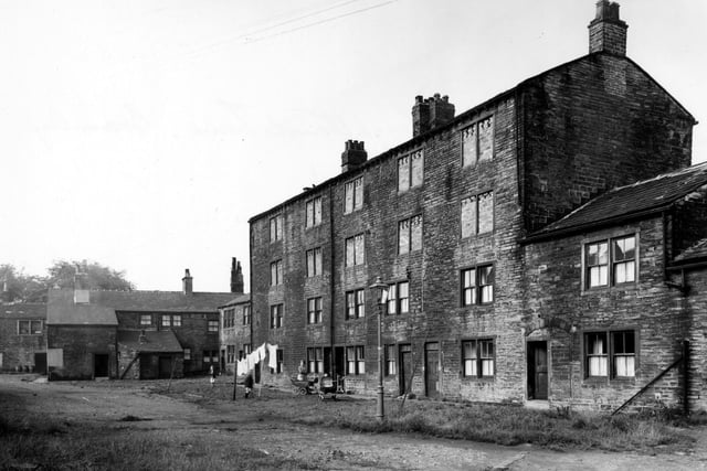 The Old Mill on Eightlands Lane pictured in August 1956 with the windows on the top two floors bricked up. Washing hanging up. Streetlamp, children, woman and prams are visible.