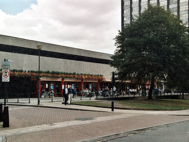 This is the front of the Grosvener Casino and public house. There are people sitting outside the pub at tables and a few walking along the street.