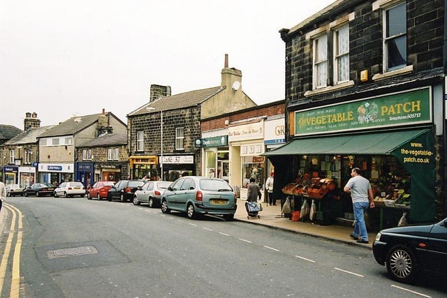 Shops on Yeadon High Street In October 2003. They include the Co-op pharmacy, moving right, Box of Cards, The Chocolate Shop, Bev Wood Florist, Cafe 37, Lloyd's Pharmacy, Best Wishes Greeting Cards, Greggs bakery and The Vegetable Patch.