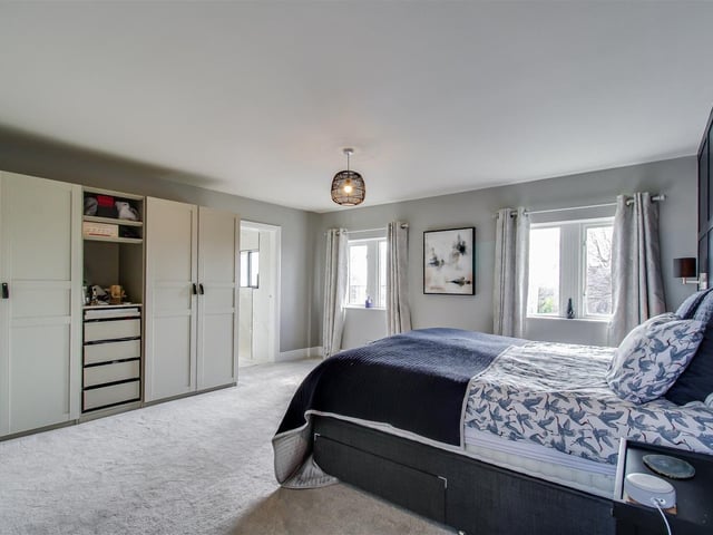 The principal bedroom has decorative wall panelling, a central heating radiator, and access to an en suite shower room.
