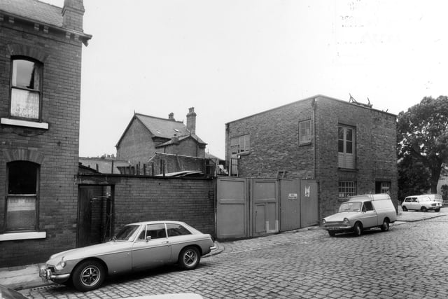 Cross Greenhow Avenue, showing the side and rear of the premises of T. & L. Ford, builders, plumbers and joiners, which faces onto Burley Road, just seen on the right. To the left of the image is no. 5 Cross Greenhow Avenue. Pictured in July 1975.