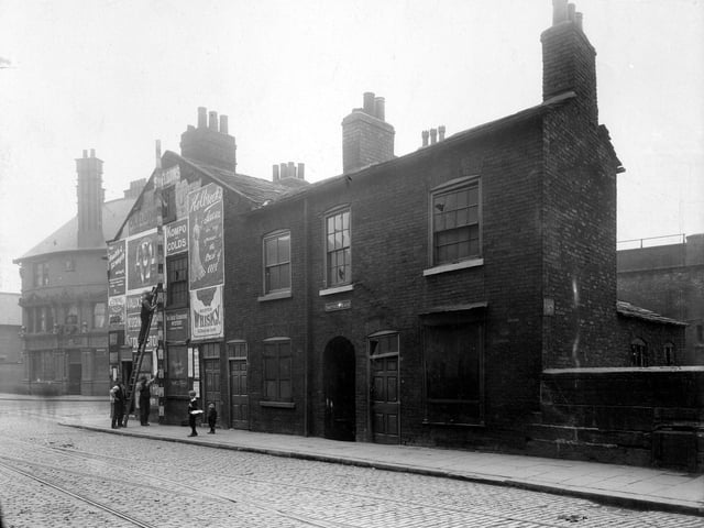 York Street at the junction with Duke Street in July 1907. The ornate facade of the Lloyds Arms public house is on Duke Street, to the left. It was demolished in 1994 to build the inner city loop road. Workmen are measuring shop property, this was number 48 York Street, run by Sarah Ann Curtis.