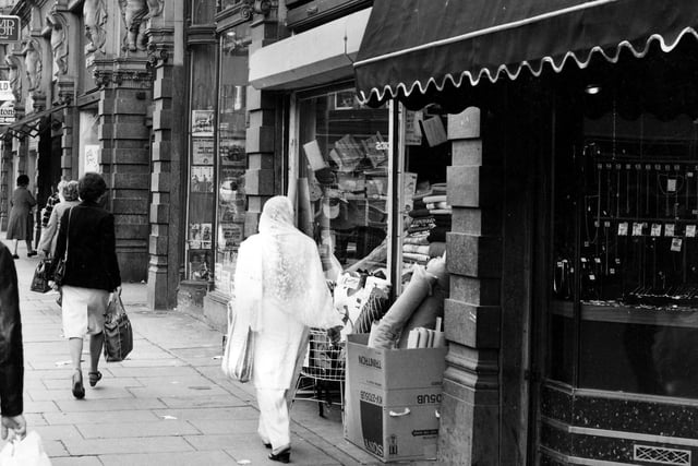 Shoppers on Vicar Lane in May 1984. Kirkgate Market Buildings are on the right. Joseph Hemsworth, jeweller, is in the foreground, then Economic Woollen Company, fabrics, and Cut Price Records.