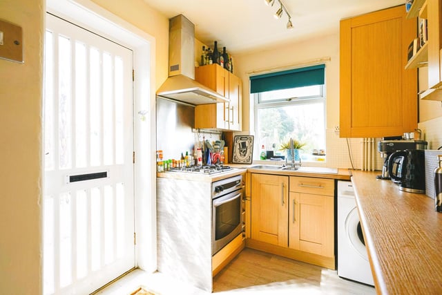 The kitchen has a range of matching wall and base units with a gas hob, integrated oven, plumbing for a washing machine and a pantry cupboard.