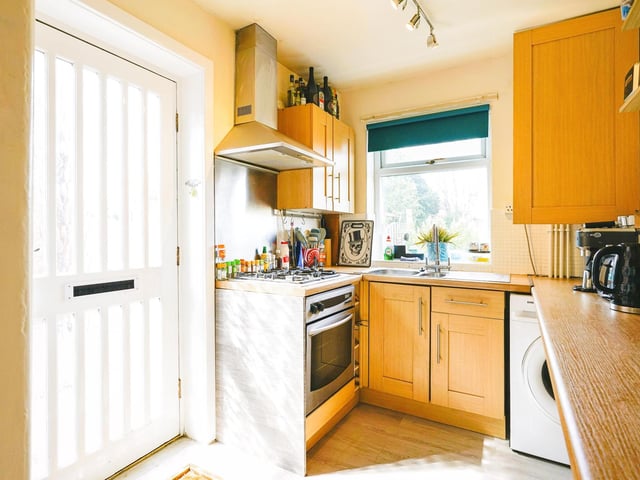 The kitchen has a range of matching wall and base units with a gas hob, integrated oven, plumbing for a washing machine and a pantry cupboard.