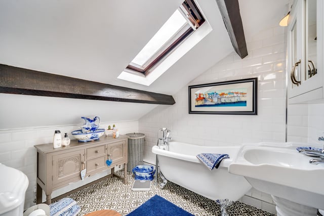 The tiled house bathroom has a traditional roll-top bath, and skylight window.