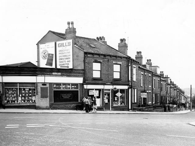 Aston Road seen from the junction with Highfield Road in May 1979. On the left is Aston Pharmacy then a newsagents/tobacconists. A group of children and a dog are gathered outside the shops.