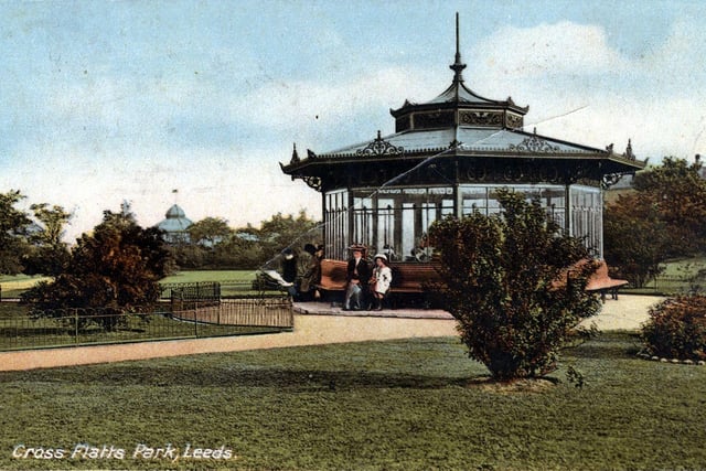 A colour-tinted postcard of Cross Flatts Park with a postmark of May 11, 1913. An octagonal shelter has seating around the outside. The bandstand is just seen in the background.