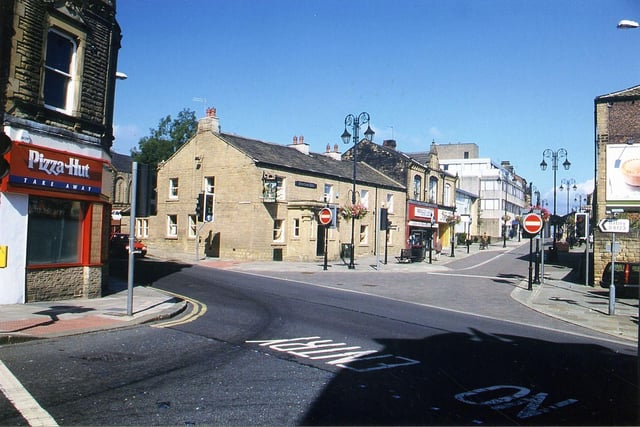 August 1999 and in focus is Fountain Junction, from South Queen Street with Fountain Street on the left, Queen Street up ahead and High Street to the right. Pizza Hut is seen on the corner on the left, and the Fountain Inn and Benefactory (Khalid Fashions and Faces Hair and Beauty Salon) in the centre.