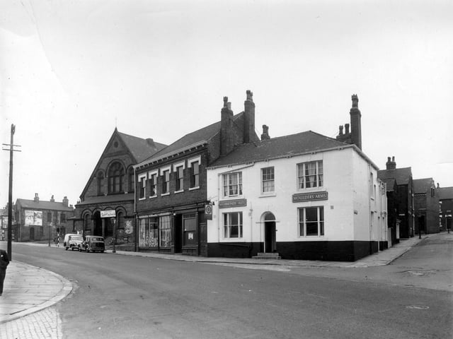 A view of the junction of Cherry Row with Lincoln Road in August 1958. This part of Burmantofts was also known as Newtown. At the very left edge is Lincoln Field Row, then, with advertising on the side of the end property, is Lincoln Street. The building with the arched doors and windows is the old Lincoln Fields Wesleyan Methodist Sunday School, at number 6 Hill Street, located at the junction with Cherry Row and Hill Street. It has a sign above the entrance advertising 'Empire House-Farmlands Egg Stores Ltd.' In the centr