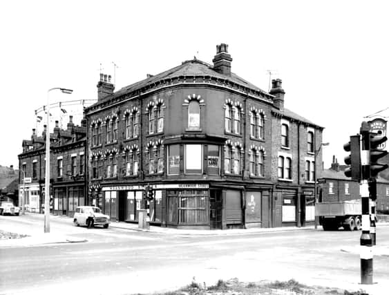 The junction of Barrack Street and Meanwood Road pictured in April 1967. In the background, the metal frame of a gasometer is visible. Barrack Street runs from the left edge. In the centre of the view is the former Meanwood Stores at number 60 Meanwood Road. Posters advertising a 'Closing Down Sale' are in the windows, the shop closed a month before this photo was taken. The premises of Rayman Financiers Ltd, can be seen at number 54 Meanwood Road with the street continuing to the right edge.