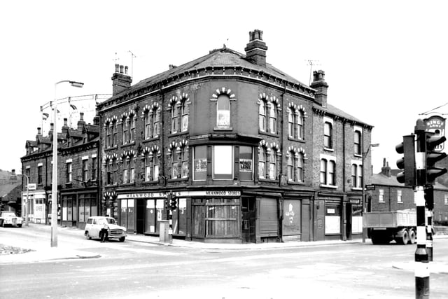 The junction of Barrack Street and Meanwood Road pictured in April 1967. In the background, the metal frame of a gasometer is visible. Barrack Street runs from the left edge. In the centre of the view is the former Meanwood Stores at number 60 Meanwood Road. Posters advertising a 'Closing Down Sale' are in the windows, the shop closed a month before this photo was taken. The premises of Rayman Financiers Ltd, can be seen at number 54 Meanwood Road with the street continuing to the right edge.