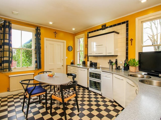 The kitchen features a range of wall and base units with a corian work surface, a stainless steel inset sink and a drainer with mixer tap and tiled splash back.