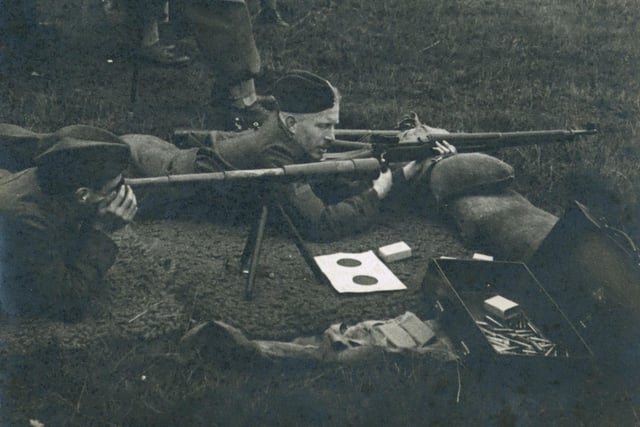 A black and white photograph of Leeds Home Guard in Training entitled 'Firing of the .300 Rifles at Harewood Park, Sept 1940'. Sniper training Lee Enfield 303 target shooting with telescope. The rifle did not have a telescopic site, so the spotter would use the telescope to locate the target and direct the sniper.
