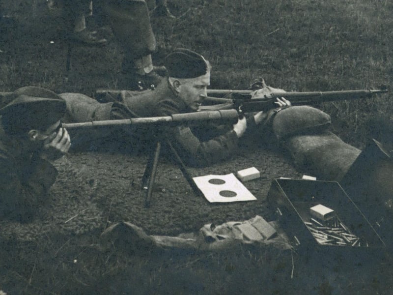 A black and white photograph of Leeds Home Guard in Training entitled 'Firing of the .300 Rifles at Harewood Park, Sept 1940'. Sniper training Lee Enfield 303 target shooting with telescope. The rifle did not have a telescopic site, so the spotter would use the telescope to locate the target and direct the sniper.