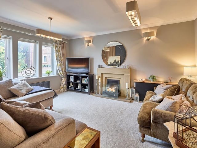 The spacious room has a triple window at the front, a striking stone fireplace and a contemporary feature wall.