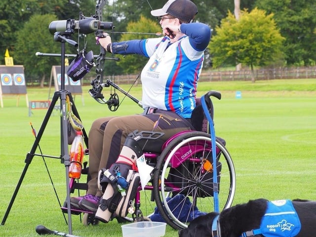 Amanda Davidson practicing archery, with previous support dog Jupiter in tow