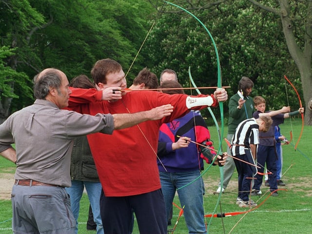 Bowmen of Adel in action in May 1996.  Club chairman Cedric Abbott shows Simon Reeve of Oakwood how to use a bow.