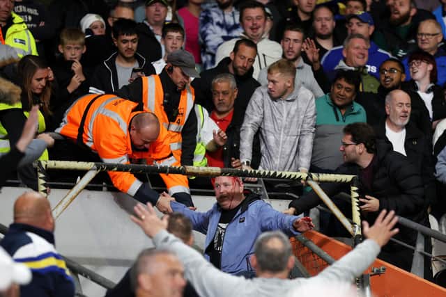 AWAY END - A Leeds United fan interacts with stewards after falling onto the tv gantry during the Sky Bet Championship match between Hull City and Leeds United at MKM Stadium. Pic: George Wood/Getty Images