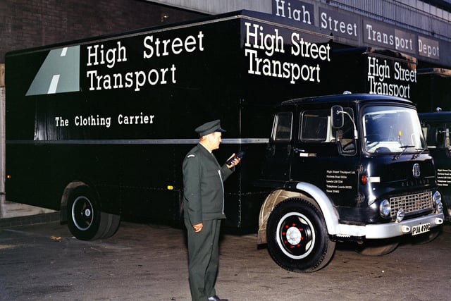 A photograph of two High Street Transport lorries outside of the High Street Transport depot. There is a lorry driver stood in front of the vehicle holding a remote control. This is a Burton's company photograph. Pictured in June 1973.