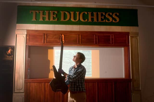 Esther Amis-Hughes pictured at Leeds City Museum with guitar belonging Jez Willis from the Leeds Band Utah Saints in front of a Replica sign of the Duchess of York.