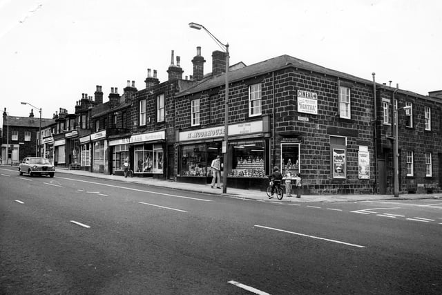 Headingley's Otley Road showing the junction with Cottage Road on the right. Shops in the picture include H. Moorhouse, grocers, at nos. 70 - 72, Mayfair Fashions at no. 78 and J. C. Cook, butcher at no. 78. There is an advertisement for Cottage Road Cinema, which is showing the film 'Agatha'. Other billboards advertise Kleenex Tissues and Radox. Three children are on the corner including a boy on a bicycle. Pictured in June 1980.