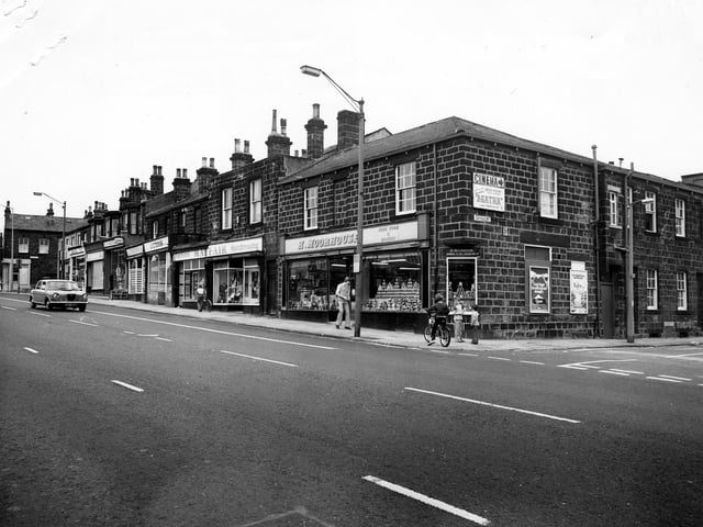 Headingley's Otley Road showing the junction with Cottage Road on the right. Shops in the picture include H. Moorhouse, grocers, at nos. 70 - 72, Mayfair Fashions at no. 78 and J. C. Cook, butcher at no. 78. There is an advertisement for Cottage Road Cinema, which is showing the film 'Agatha'. Other billboards advertise Kleenex Tissues and Radox. Three children are on the corner including a boy on a bicycle. Pictured in June 1980.