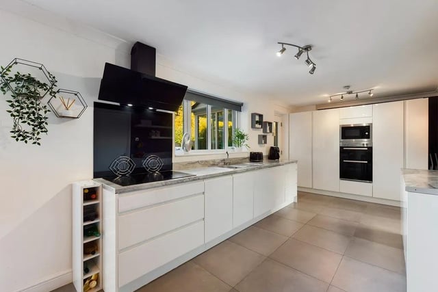The dining kitchen is fitted with a matching range of modern floor-to-ceiling integrated storage in white gloss finish with complimentary work surfaces, a stainless steel sink with a mixer tap