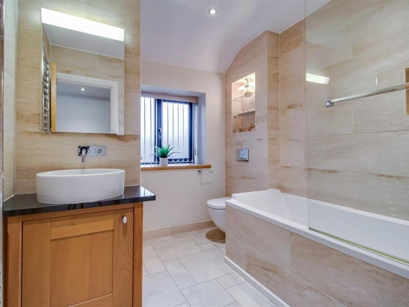The main family bathroom features a four piece suite comprising of a concealed cistern low flush w.c., a wash basin with a granite work surface over a base unit, and a ceramic tiled bath with a flush fitting mixer shower.