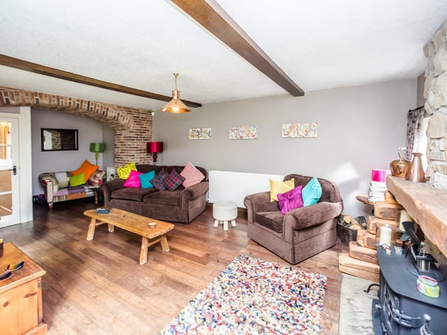 Open brickwork, stone and wood elements add rustic appeal to this family room within the cottage.