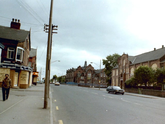 Roundhay Road looking south-east from near the junction with Harehills Road. On the left is Lambton Place, then the Gas Gallery on Roundhay Road. This along with other shops on the street is boarded up due to the riots which were taking place in Chapeltown around that time, but it is said to be 'Open for business as usual'. On the right is the New Leeds Constitutional Club then after the junction with Shepherds Lane is Harehills County Primary School.