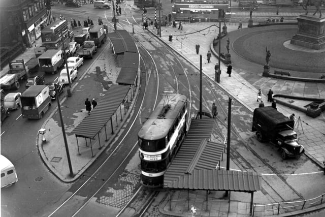 An elevated view of City Square in January 1956. In the foreground is a tram alongside a covered tram stop. Lorries, cars, trams and buses are on the road. In the upper right is the statue of Edward, The Black Prince.