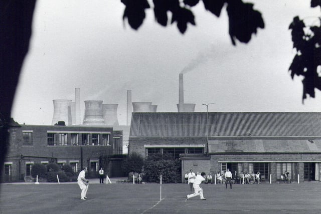 A game of cricket taking place on the sports field for staff at John Waddington's printing factory, off Wakefield Road, Thwaite Gate in the 1960s. The view looks north-east, and the cooling towers of Skelton Grange Power Station can be seen above the rooftops.