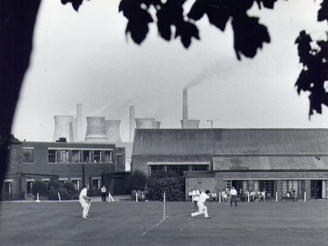 A game of cricket taking place on the sports field for staff at John Waddington's printing factory, off Wakefield Road, Thwaite Gate in the 1960s. The view looks north-east, and the cooling towers of Skelton Grange Power Station can be seen above the rooftops.