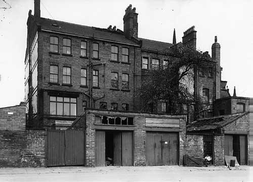 Two properties on Lodge Street in March 1966 . These were through properties, going through to Hillary Chambers at numbers 4 and 4a Hillary Place. A row of garages is in the foreground.