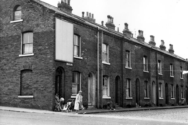 A view from Oatland Road along Oatland Place. Number 1 is on the corner, where a woman and children are in the doorway the numbers run in ascending order towards the right. Pictured in August 1967.