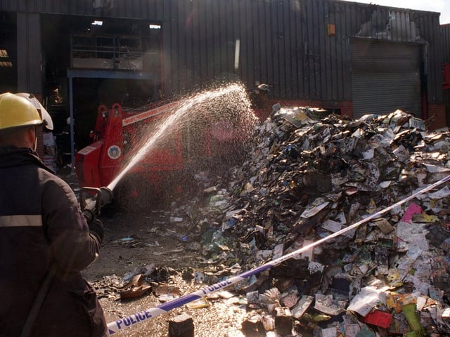 A fireman dampens down debris after a fire at the Prince of Wales Hospice store and computer software premises in September 1997.