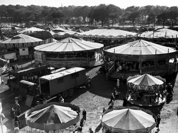 Woodhouse Feast on Woodhouse Moor in September 1955. People can be seen on or near various rides and stalls. Woodhouse Lane is visible in the background.