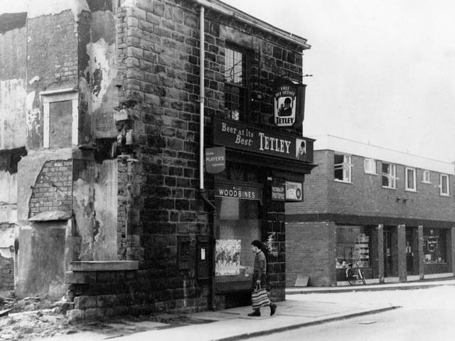 An off-licence on Victoria Road in 1967. It served as Victoria Road Post Office - a stamp dispenser and post box set in the wall. There is a young boy with a shopping carrier in the foreground. Two storey flat roofed brick building, is two shops with flats above them. They were built to replace the old Post Office. The new Post Office was owned by Mr. and Mrs. Vickerman and the far shop was originally a grocers owned by Mr. and Mrs. Brookes. Bicycle leaning against front window. Beginning of stone houses on Victoria Road also visible.