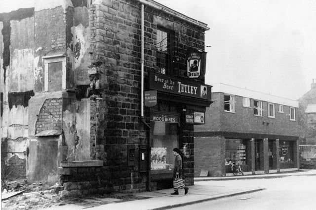 An off-licence on Victoria Road in 1967.  It served as Victoria Road Post Office - a stamp dispenser and post box set in the wall. There is a young boy with a shopping carrier in the foreground. Two storey flat roofed brick building, is two shops with flats above them. They were built to replace the old Post Office. The new Post Office was owned by Mr. and Mrs. Vickerman and the far shop was originally a grocers owned by Mr. and Mrs. Brookes. Bicycle leaning against front window. Beginning of stone houses on Victoria Road also visible.