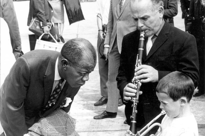 Jazz trumpeter Louis Armstrong is seen arriving at Leeds and Bradford Airport. He was met by seven-year-old Enrico Tomasso from York Road, playing 'Basin Street Blues' with his father Ernie. Louis was due to appear at Batley Variety Club